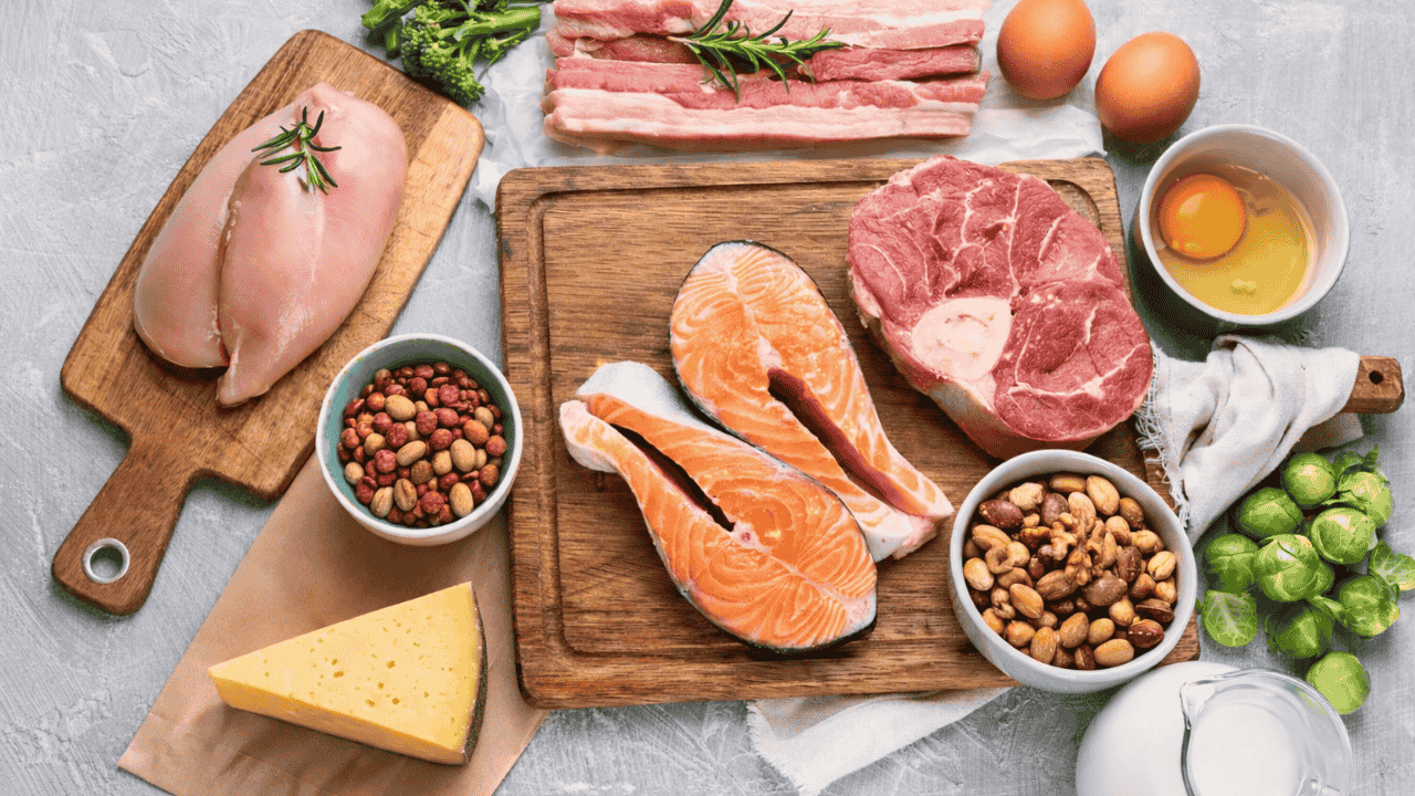 Proteinreiche Lebensmittel: Hähnchen, Lachs, Rindfleisch, Eier, Nüsse und Käse auf Schneidebrettern