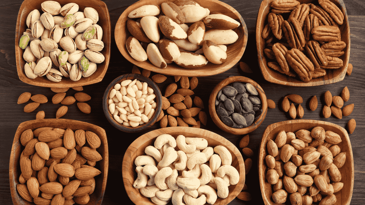 Verschiedene Nüsse und Kerne in Holzschalen auf dunklem Tisch