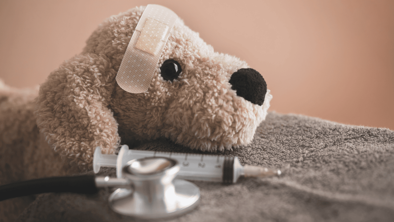 Stoffhund mit Pflaster am Kopf neben Spritze und Stethoskop