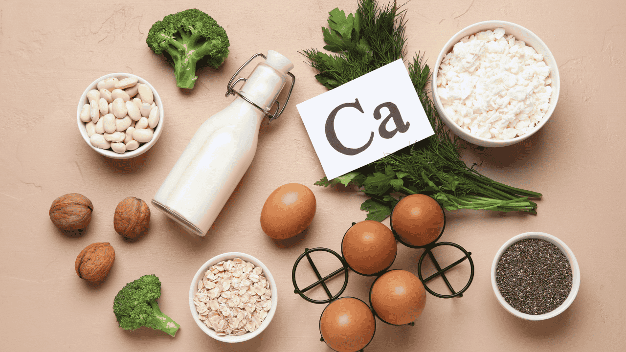 Kalziumreiche Lebensmittel wie Milch, Eier, Brokkoli, Nüsse, Haferflocken und Hüttenkäse auf einem Tisch.